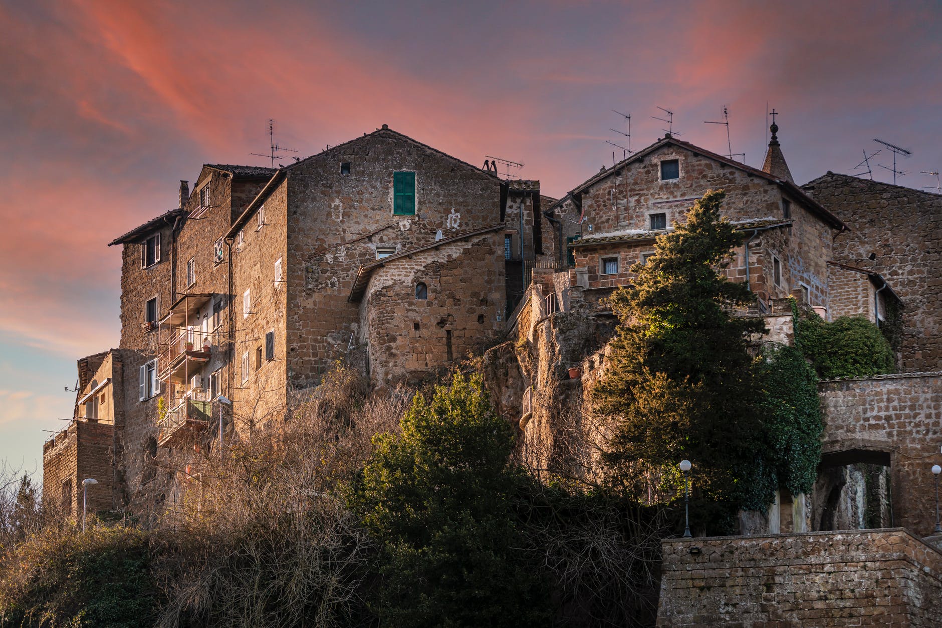 facades of aged stone houses located on hill under sunset sky